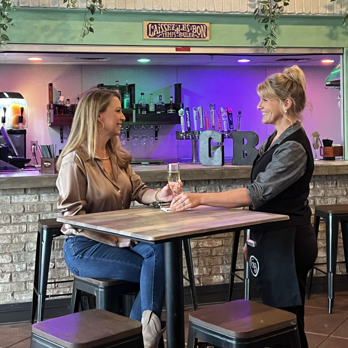 A Georgia Blue server toasting with a guest at the bar